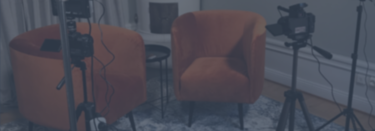 Två orangea fåtöljer och kameror på stativ inriktade mot dem i ett inspelningsrum.